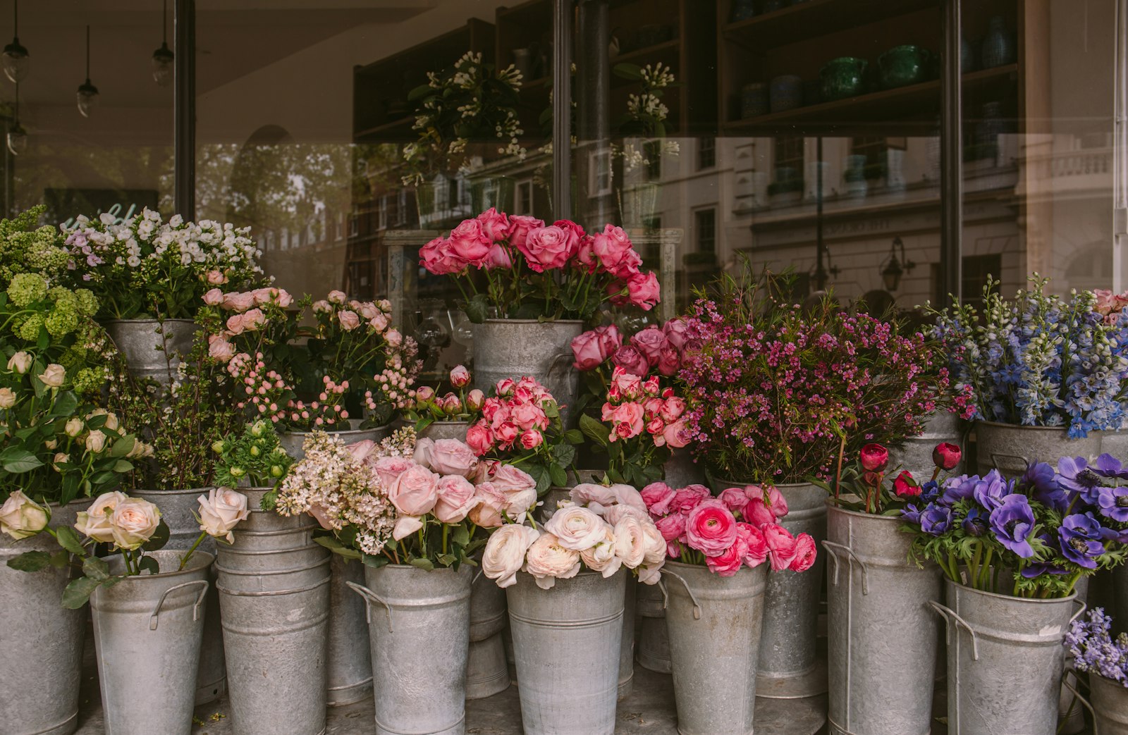 A flower shop with buckets of fresh blooms lined up on the pavement
