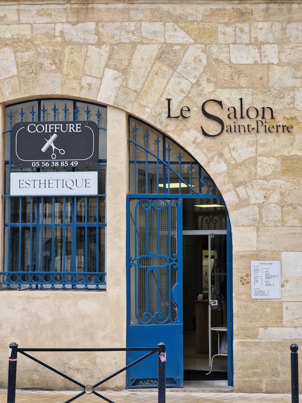 The limestone façade of Le Salon Saint-Pierre in Bordeaux, with its blue wrought-iron door standing open
